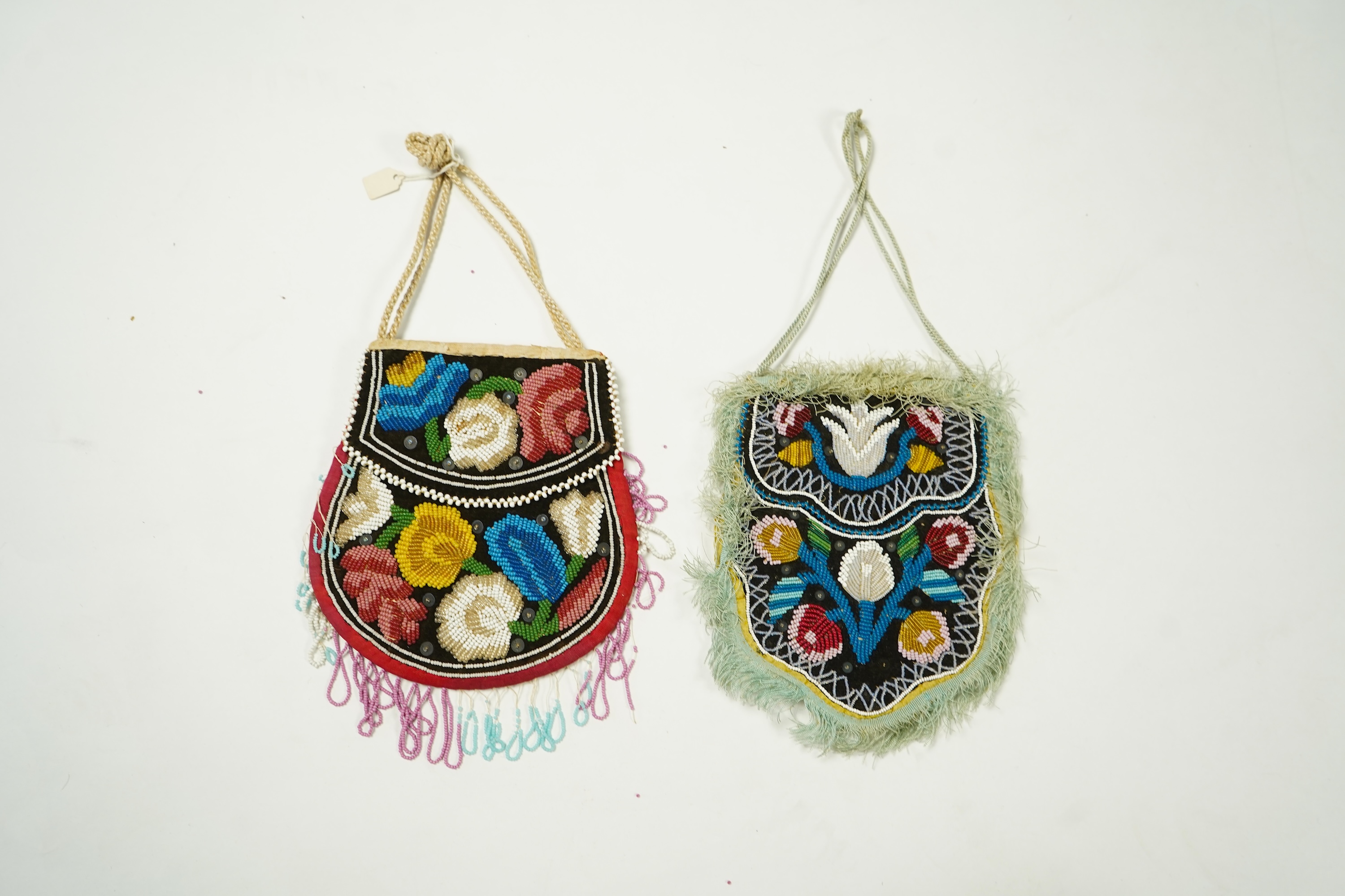 Two Native American Iroquois beaded bags. One edged with fine pale blue silk fringing, the other larger with bead worked fringing. Largest 16.5cm high. Condition - The blue fringed bag has a few sequins missing and the f
